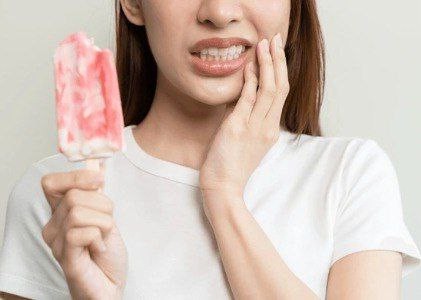 Sensitive Teeth Woman reacting to cold popsicle due to sensitive teeth